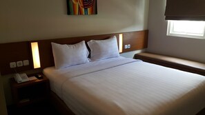 A hotel room with a bed, a bedside table with a phone, and a window with a view.