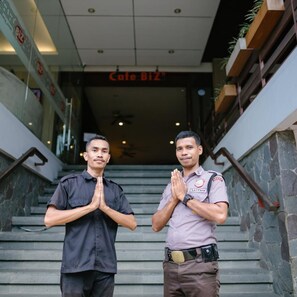 Two individuals standing on a staircase with a sign reading 'Cafe Biz' above.