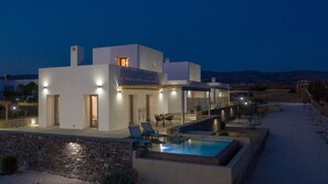 Een modern huis met een zwembad, terras en een stenen muur.