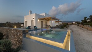Una casa moderna con piscina, pareti in pietra e area relax esterna.