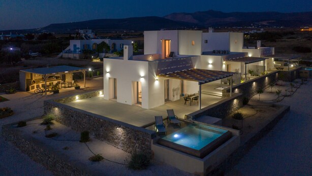 Una casa moderna con piscina, area relax esterna e un muro in pietra.