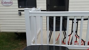 A black table with metal legs, a white railing, and a door with a black frame. - Above & Beyond Caravans4hire Lyons Robin Hood Rhyl (Rhyl)