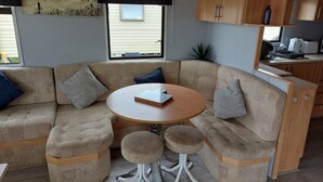 A cozy corner with a beige sectional sofa, a small round table, and matching ottomans. - Above & Beyond Caravans4hire Lyons Robin Hood Rhyl (Rhyl)