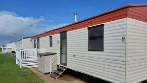 A row of mobile homes with a red roof, each featuring a window and a door. - Above & Beyond Caravans4hire Lyons Robin Hood Rhyl (Rhyl)