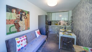 A modern kitchen with a dining area, a sofa with colorful pillows, and a large abstract painting on the wall. - Sapphire house amalfi coast sea view (Minori)