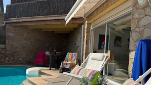 A poolside area with lounge chairs, a table, and a stone wall. - Apartment with private pool only 400 mts from the beach . Very close Sa Riera. (Sa Riera)