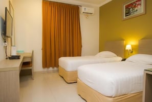 Une chambre d’hôtel avec deux lits, un bureau, une chaise, une fenêtre avec des rideaux et un climatiseur fixé au mur.