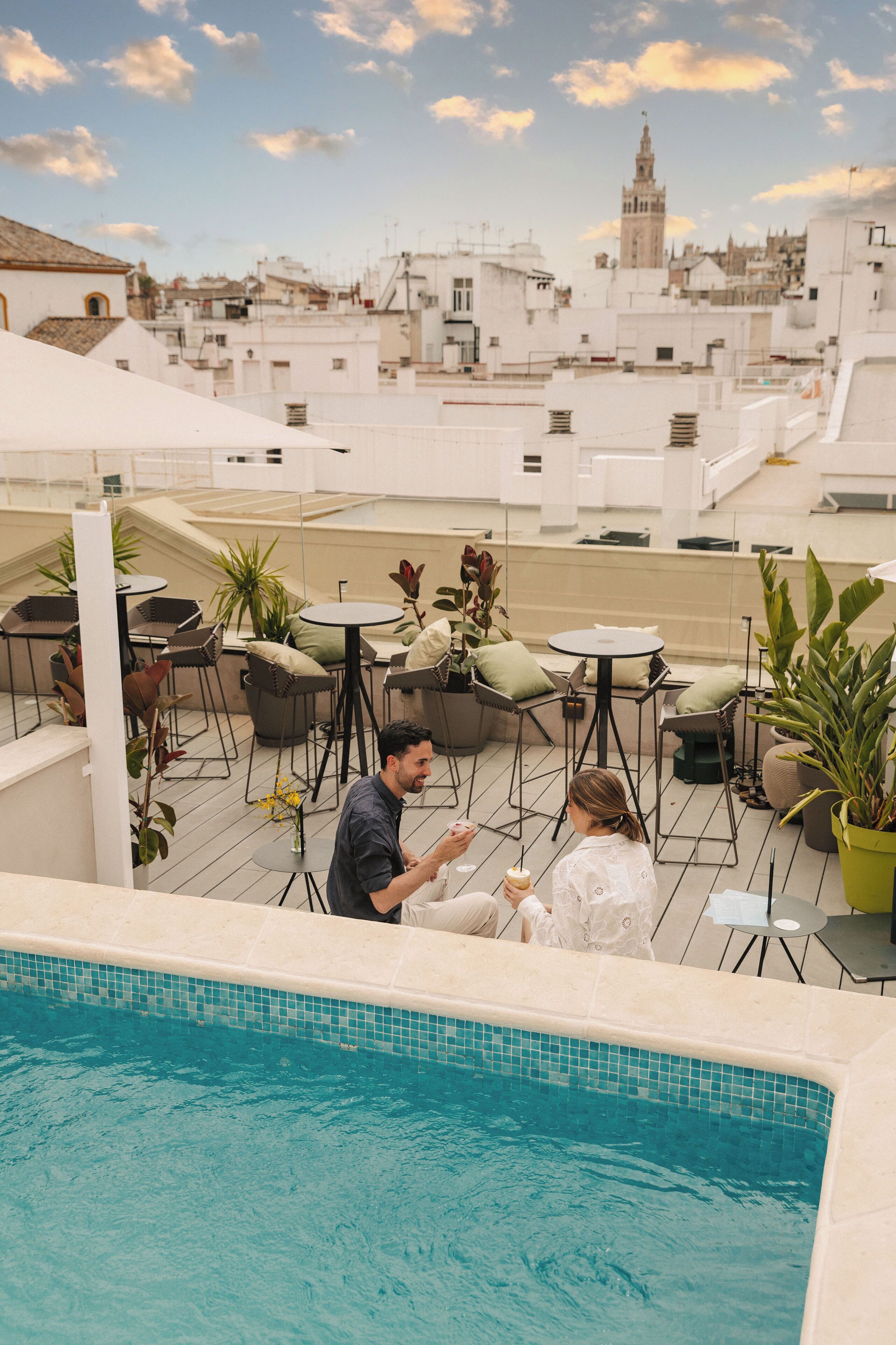 Zona de piscina al terrat amb seients a l'aire lliure i vista a l'horitzó urbà.