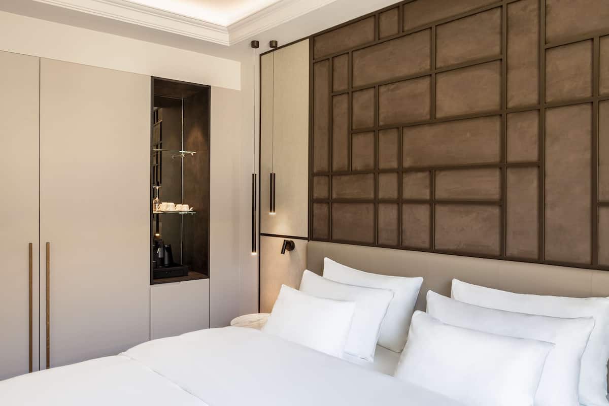 A modern bedroom with a large bed, a built-in wardrobe, and a wall-mounted shelf.