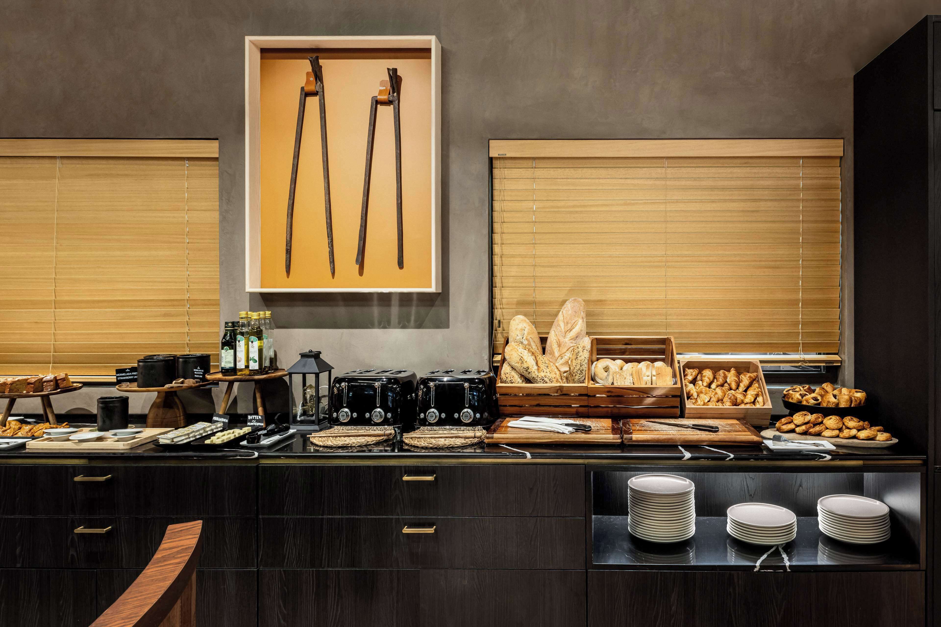 A buffet setup with bread, pastries, and condiments.