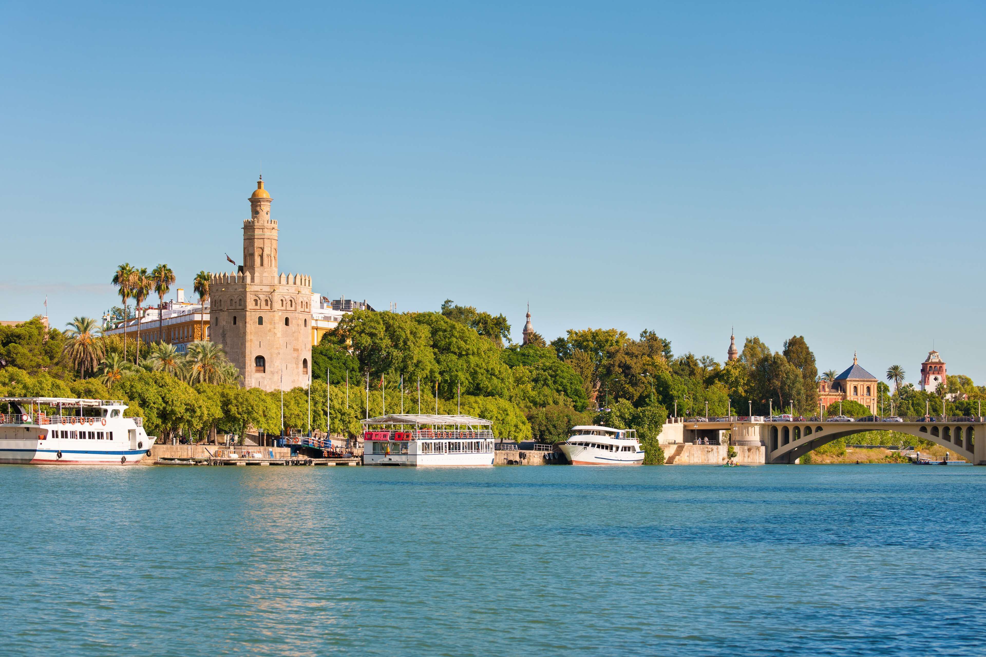 A historic building with a tower, a bridge, and boats on the water.