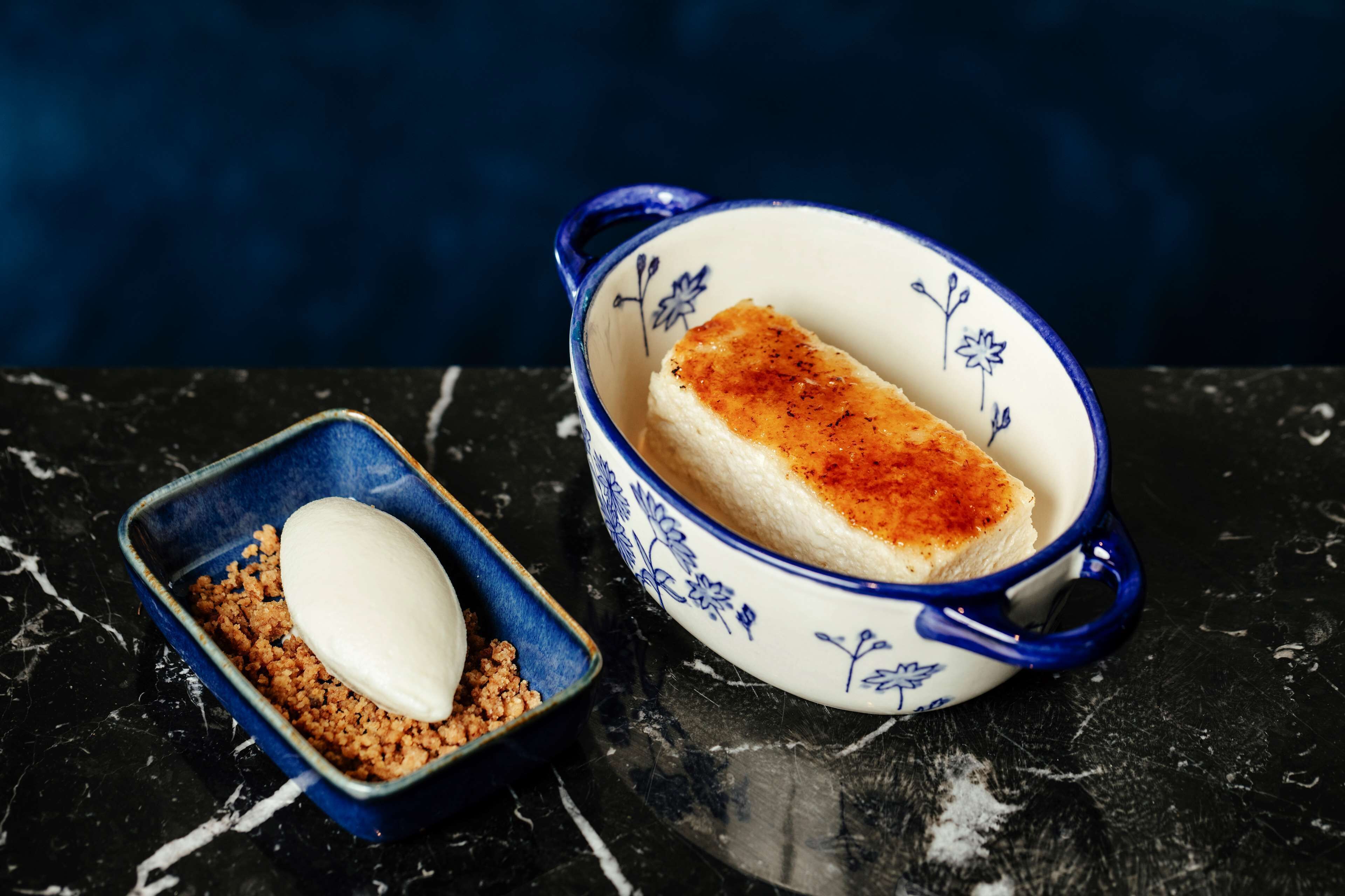 Un postre en un cuenco de estampado floral sobre una superficie de mármol.