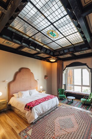 A hotel room with a large bed, a green armchair, a small table, and a large window. - Casablu Hotel (Valparaiso)