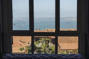 Une vue à travers une fenêtre, avec un paysage urbain et de l’eau en arrière-plan.