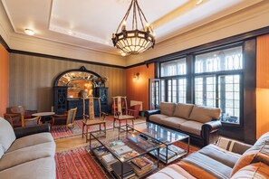 Un salon spacieux doté d’une cheminée, de sièges confortables et de grandes fenêtres.
