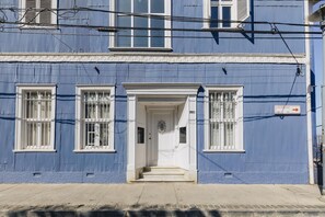 A blue building with a white door and windows, a street sign, and a mailbox.