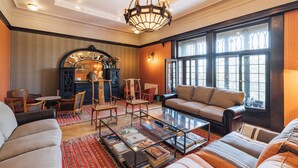 Un salón amplio con chimenea, asientos cómodos y ventanas grandes.