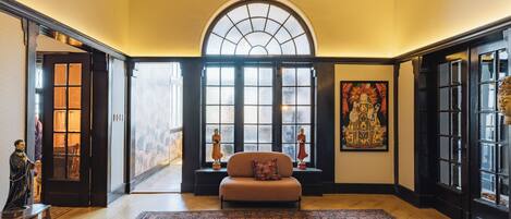 A spacious room with a large window, a sofa, a patterned rug, and a Buddha statue.