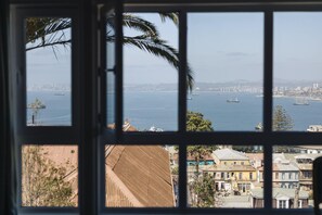 Une vue à travers une fenêtre, avec un paysage urbain et de l’eau en arrière-plan.