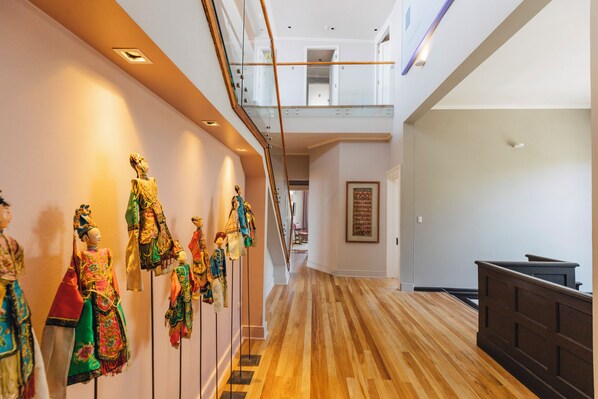 A hallway with wooden flooring, a staircase, and a mezzanine level.