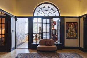 A room with a large arched window, a sofa, a rug, and a statue. - Casablu Hotel (Valparaiso)