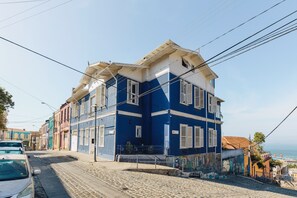 A multi-story building with a blue facade and white trim, located on a cobblestone street. - Casablu Hotel (Valparaiso)