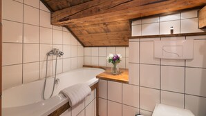 Un baño con techo de madera, una bañera, ducha y retrete.