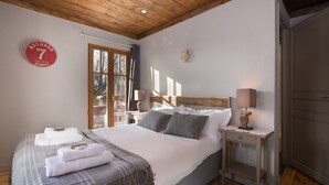 Un dormitorio con una cama grande, techo de madera, una mesita de noche con lámpara y un reloj de pared.