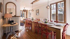 Un comedor con una mesa de madera dispuesta para una comida, sillas rojas y piso de madera.