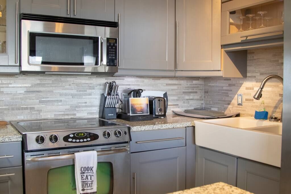 A modern kitchen with stainless steel appliances, a microwave, a toaster, and a sink.