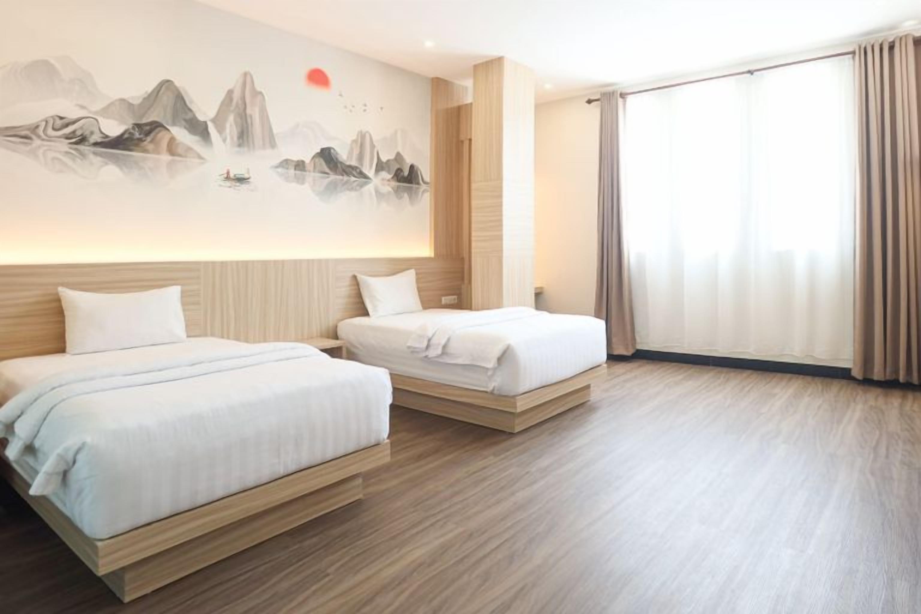 A hotel room with two beds, a large window with curtains, and a wall mural.