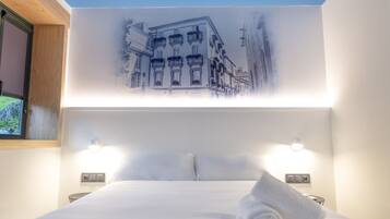 A hotel room with a large bed, two bedside tables, a wall-mounted light, and a window with a view of buildings.