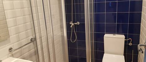A bathroom with a glass-enclosed shower, a white sink, and a toilet.