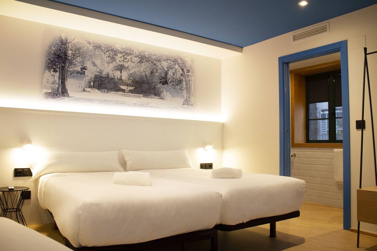 Una habitación de hotel con una cama grande, dos mesitas de noche y una obra de arte colgada en la pared.