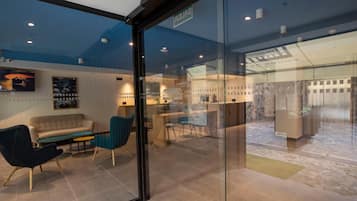 Een modern interieur met een glazen scheiding, een bank, een stoel en een eethoek met een tafel en stoelen.