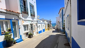 A narrow street lined with buildings painted in blue and white, with a clear view of the sea in the background. - Family-friendly villa has private pool, short walk to Burgau Beach (Burgau)