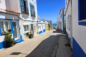 Eine enge Straße gesäumt von in Blau und Weiß gestrichenen Gebäuden, im Hintergrund ist das Meer deutlich sichtbar.