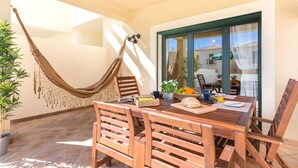 A wooden table with chairs, a hammock, and a potted plant. - Family-friendly villa has private pool, short walk to Burgau Beach (Burgau)