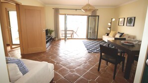A living room with a sofa, dining table, and chairs, a sliding glass door leading to a balcony, and a ceiling fan. - Family-friendly villa has private pool, short walk to Burgau Beach (Burgau)