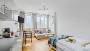 A modern, well-lit room with a kitchen area, a dining table, a sofa, and a bed. - ShortStayPoland Plac Mirowski (Warsaw)
