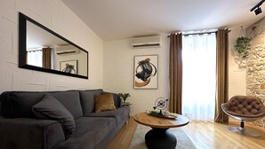 Una sala de estar moderna con un sofá gris, una mesa de centro redonda y una pared de acento de piedra.