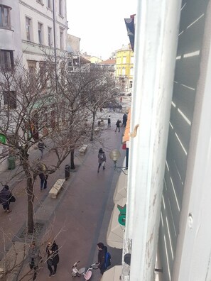 Straßenansicht mit Gebäuden, Bäumen und Fußgängern.