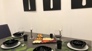 A dining table set with black plates, silverware, and a charcuterie board with cheese, meats, and crackers. - Apartment Porta Aurea (Pula)