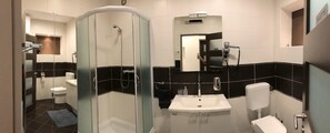 Ein modernes Badezimmer mit einer gläsernen Duschkabine, einem weißen Waschbecken und einer Toilette.