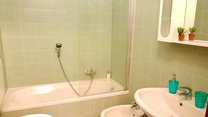 Une salle de bain équipée d’une baignoire, de toilettes, d’un bidet et d’un lavabo.
