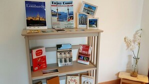 Une étagère avec des livres de voyage et des cartes postales, un vase rempli de fleurs et une petite table.