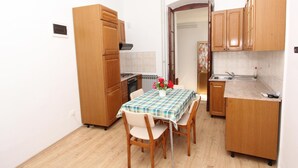A compact kitchen with wooden cabinets, a dining table with chairs, and a radiator. - Apartment Riki (Rovinj)