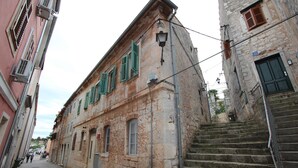 A narrow street with stone buildings, a staircase, and a sign indicating a restaurant. - Apartment Riki (Rovinj)