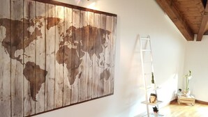 Une pièce avec une grande carte du monde en bois accrochée au mur, une échelle blanche et une étagère pour plantes.