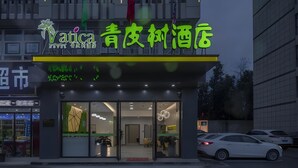 A hotel with a modern facade, large glass windows, and a neon sign.